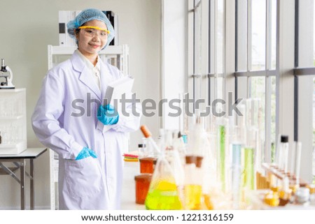 portrait of young Asian woman Scientific researcher holding book record or folder of chemical experiment research. Science college students working with chemicals in the lab at the university. 