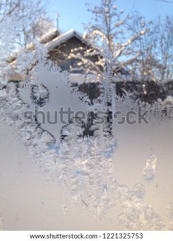 Ice pattern on winter window in a village on a sunny day. House on the background