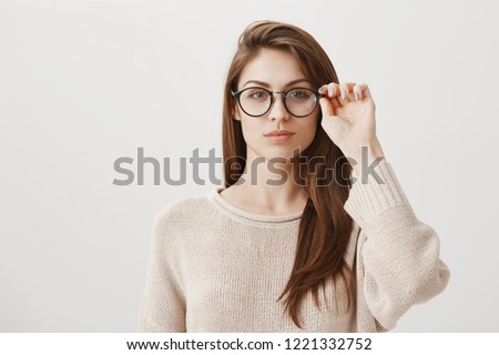 Girlfriend ready to investigate social profile of boyfriend. Portrait of good-looking smart brunette in stylish prescribed glasses looking concentrated at camera, solving issue on char over gray wall Royalty-Free Stock Photo #1221332752