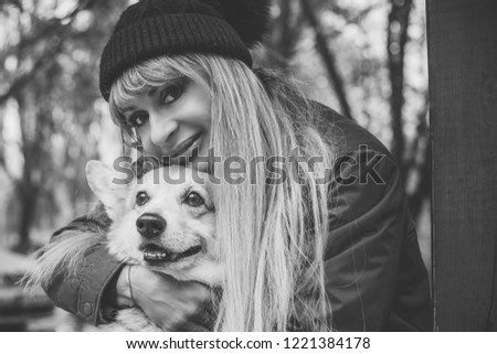 Woman with Red dog of Corgi breed for a walk in the city streets. The life of dogs in cities. Dog lover with her pet