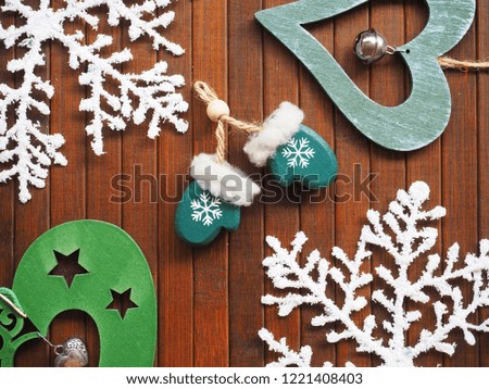 Christmas decoration with snowflakes and green mittens on wooden background. 