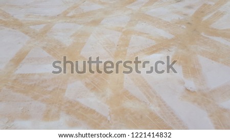 Tire tracks crossed in different directions on abnormal white sandy snow background. Anomaly color of snow cover with brown sand grains. Abnormal snow color after sandstorm. Photo without filters
