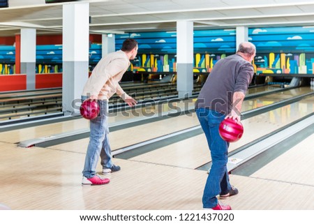 Rear view of father and son playing bowling game