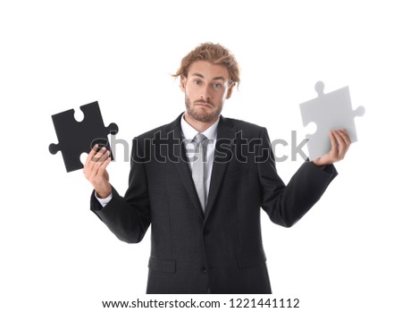 Young businessman with pieces of jigsaw puzzle on white background