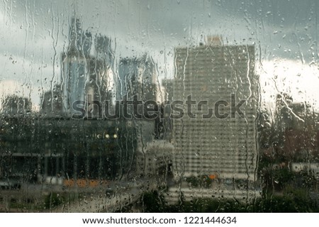 The rain streaked glass and the cityscape in the background.