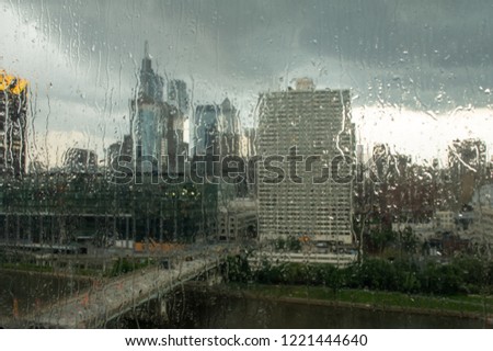 Looking through the rain drops on a glass window out over a city.