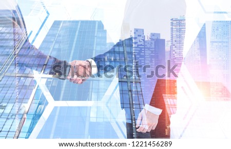Two unrecognizable businessmen shaking hands over cityscape background with hexagonal pattern foreground. Concept of partnership. Toned image double exposure
