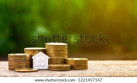 small house and a stack of golden coins in the garden. - Concept of Investment property. Royalty-Free Stock Photo #1221457147