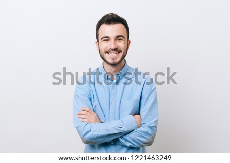 Portrait of cheerful young man in casual with crossed arms smiling over white background and looking at the camera Royalty-Free Stock Photo #1221463249