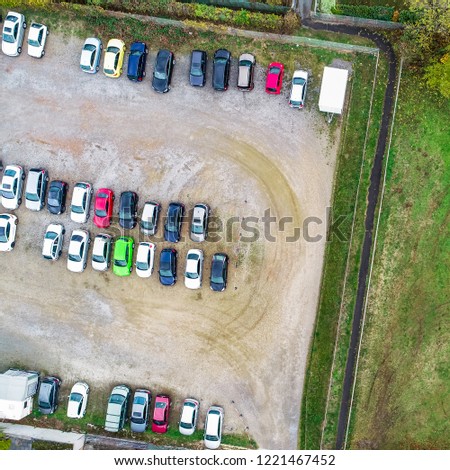Vertical aerial photo of a gravel parking lot with rows of parked cars
