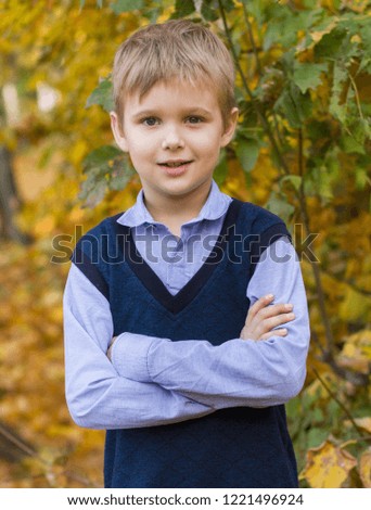 Cute boy on a walk in the park in the fall. Schoolboy after class.

