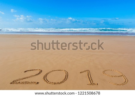 2019 inscription written in the wet yellow beach sand. Concept of celebrating the New Year.