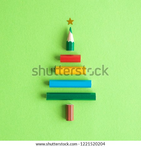 Christmas tree made of colorful pencils on pastel green background minimal holiday creative concept.