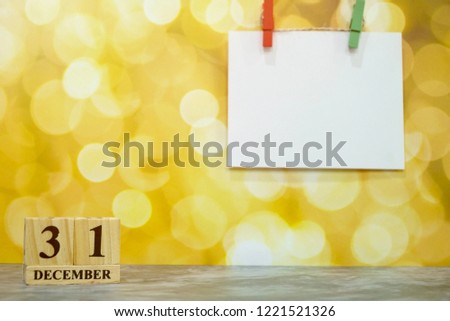 Wood calendar 31 December on golden bokeh background. Blank white paper and clip with light. Free space for any text design. Happy New year. Can be use for advertising, banner.