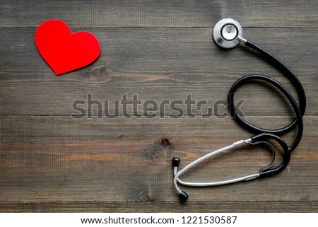 Health care concept. Stethoscope near heart sign on wooden background top view copy space