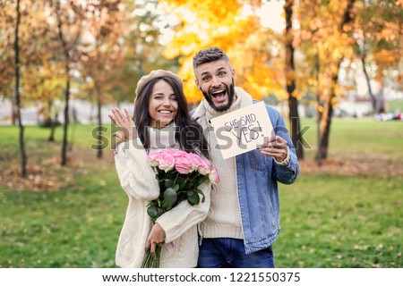 Happy couple after making proposal in autumn park Royalty-Free Stock Photo #1221550375