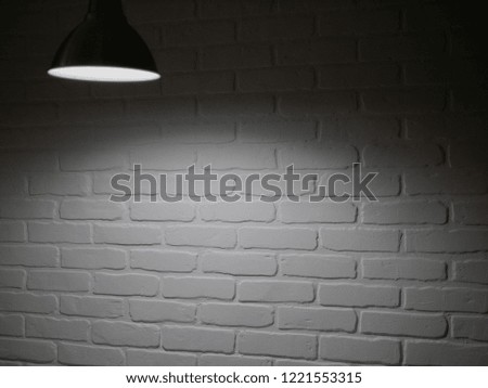 Rustic old studio with wooden table for product display or showcase and bright light shining from the top. Brick wall blurred background.
