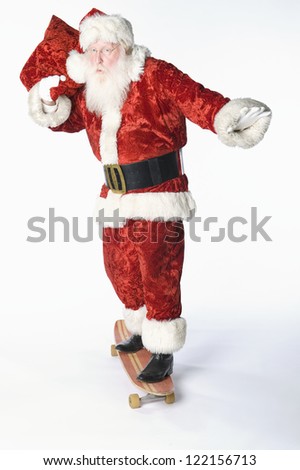 Full length of a senior Santa Claus skating on skate board carrying bag isolated over white background
