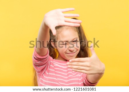 girl pretending to take a picture through her hands creating a virtual photo frame. arts hobby and leisure.