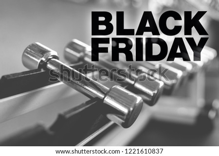 Black friday poster. Rows of dumbbells in the gym with high contrast light