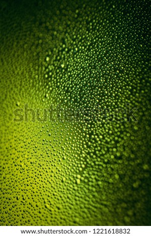 Lime droplets with bokeh. Green bottle colored wet glass surface. Fresh and appetizing. 