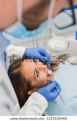 High angle view of dentist examining woman with dental equipments 