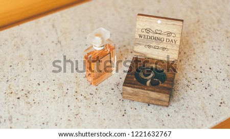 Set of wedding accesories - woman fragrance and wooden box of the wedding rings