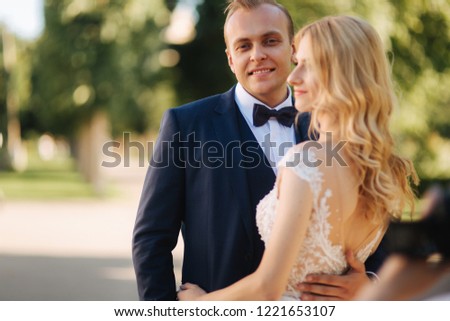 Happy young couple in their wedding day spend time in park. Green background