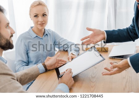 couple signing contract on clipboard with insurance agent in office