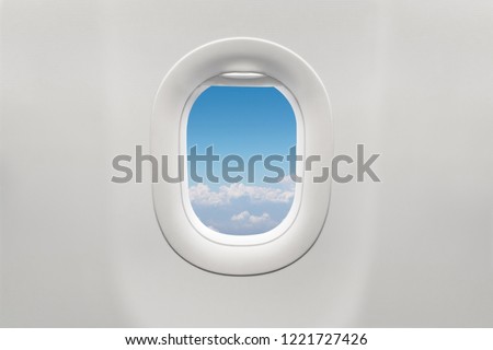 Isolated airplane window with blue sky from customer seat view Royalty-Free Stock Photo #1221727426
