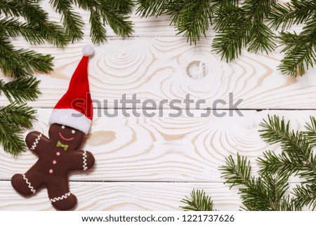 Christmas or New year background with gingerbread man in red hat and Christmas tree branches, white wooden boards, copy space, top view