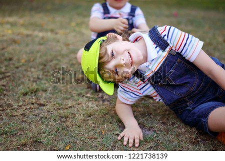 Two little kids boys having fun in a park, happy best friends playing, friendship concept. Siblings brothers, twins in family look with palms trees on background. Family vacations