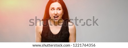 Portrait of emotional pretty confident puzzled astonished plus size model standing in studio on gray background