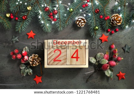 Christmas Eve Date On Calendar, December 24, with Christmas decorations and festive lights on fir twigs, frosted red berries and wooden hearts on green background Royalty-Free Stock Photo #1221768481