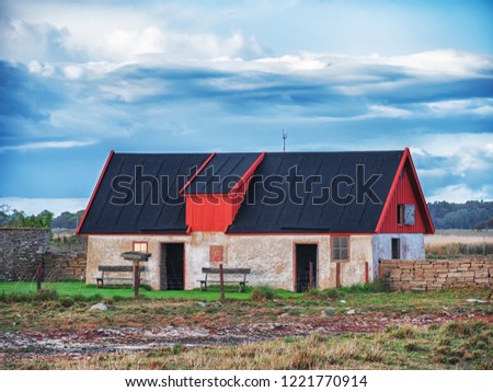 Picture of old scandinavian lighthouse and abandoned wooden houses with cloudy sky.