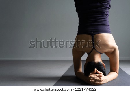 Young woman practicing yoga in  gray background.Young people do yoga indoor.Close up hands in meditating gesture. Copy space.