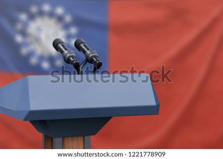 Podium lectern with two microphones and Myanmar flag in background
