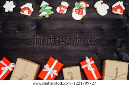 Christmas homemade gingerbread cookies and gift boxes border on dark wooden background, copy space. Top view, flat lay. Santa, snowflake, mitten, house, snowman