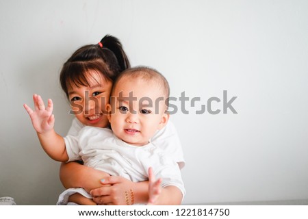 Little sister hugging her baby brother.Toddler kid meeting new sibling. Cute girl and baby boy relax at home in Japan.Family with children at home. Love, trust and tenderness.