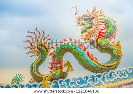 Beautiful large grimace dragons crawling on the decorative tile roof in Chinese temples. Colorful roof detail of traditional Chinese temple with dragon statue on blue sky background. Selective focus. Royalty-Free Stock Photo #1221846136