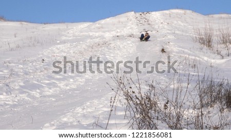 girl is rolling at high speed down high hill in sleigh in snow. happy girl playing in winter in park.