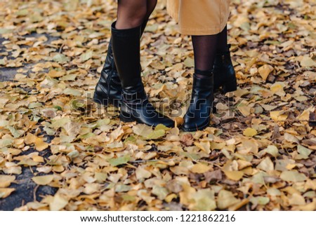 woman foot in shoeses among yellow leafs at autumn colorful park