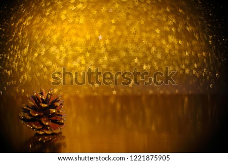 Christmas decoration of pine cone over golden star bokeh background