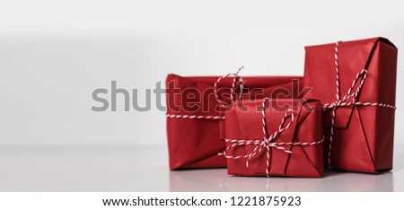 Christmas gift boxes wrapped in red paper and bow of dtriped rope on white background