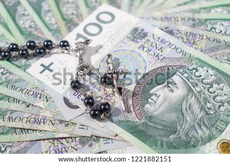 Christian cross with silver chain on a polish zloty banknotes, Relationship of religion to money, faith, spirituality and religion concept. Selective focus, white background.