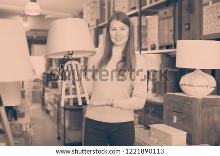 Smiling woman consumer choosing torchere in furniture shopping room