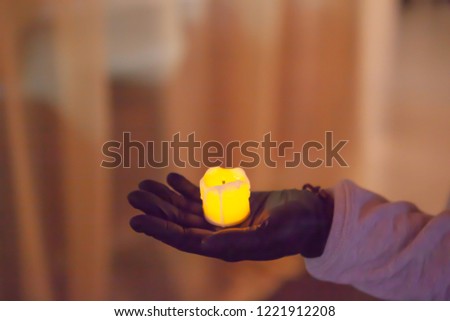Female hand in black glove holding an artificial candle