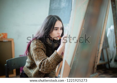 beautiful asian young woman artist paints a picture in the workshop