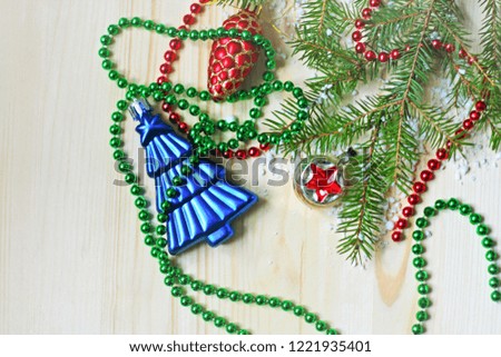 Festive background for New year and Christmas. On a light wooden surface is a branch of spruce, garland and Christmas decorations.