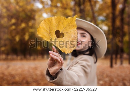 Autumn yellow leaf with cut heart in a hand Royalty-Free Stock Photo #1221936529